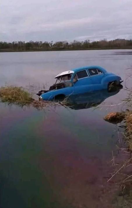 Coche azul sumergido en lago con paraguas abierto