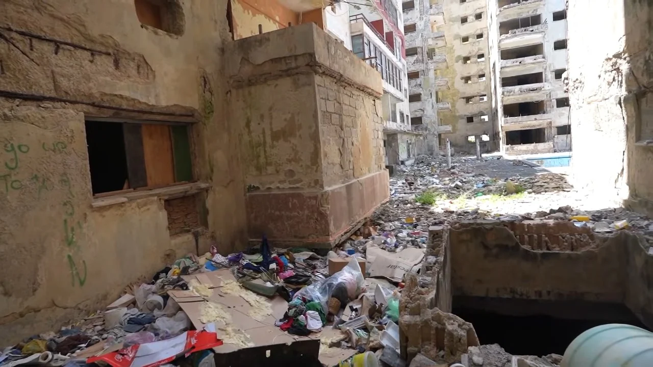 Edificio abandonado en ruinas con basura alrededor.