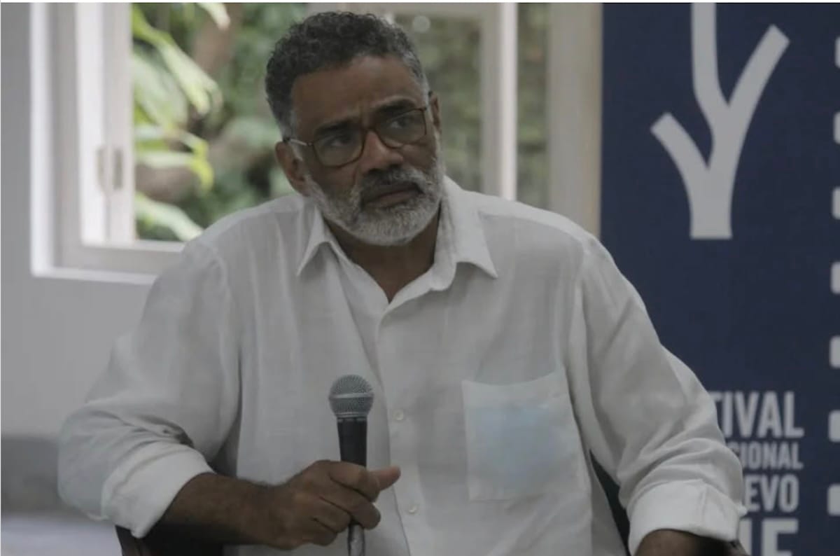 Hombre mayor con camisa blanca hablando en micrófono