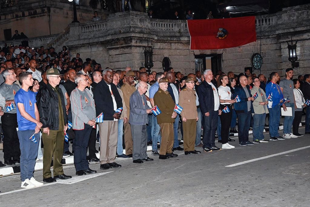 Grupo de personas con banderas en evento nocturno