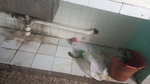 Baño sucio con basura y azulejos manchados