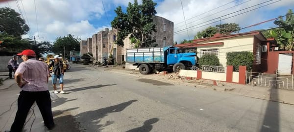 Camión azul estacionado junto a escombros en calle
