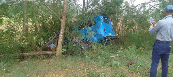 Camión azul accidentado en bosque, policía tomando fotos