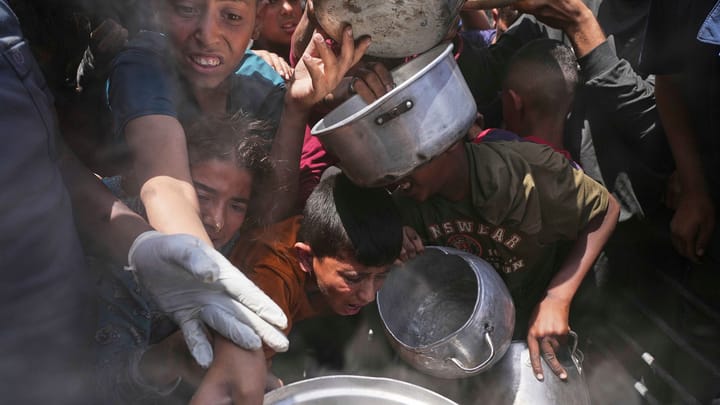 Multitud busca comida en fila con ollas.