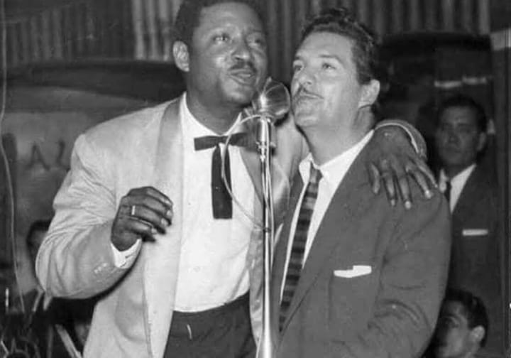 Dos hombres cantando juntos en microfono blanco y negro