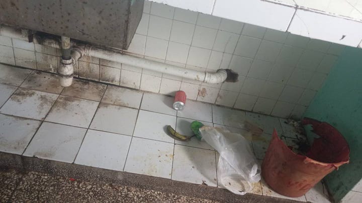 Baño sucio con basura y azulejos manchados