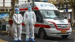 Sanitarios en trajes de protección junto a ambulancia