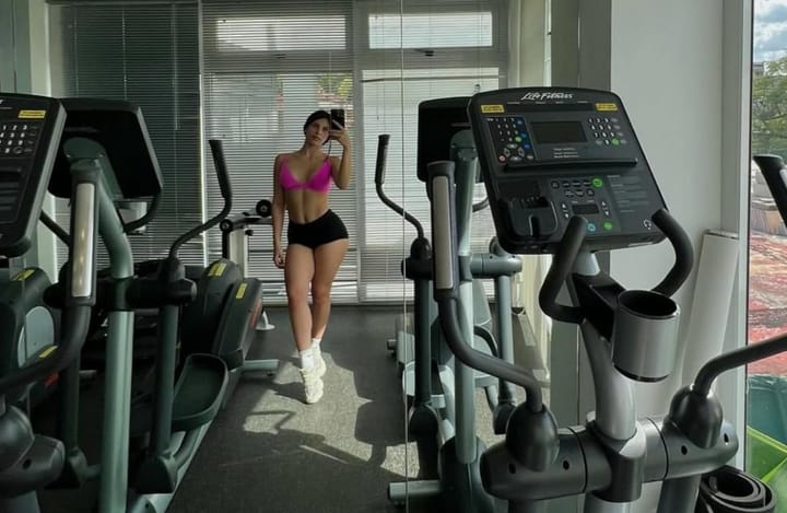 Mujer posando en gimnasio con máquinas de cardio
