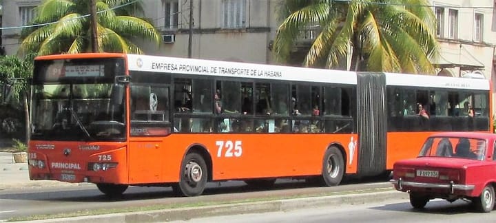 Autobús articulado naranja en calle de La Habana.