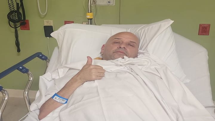 Paciente en cama de hospital, hace gesto positivo.