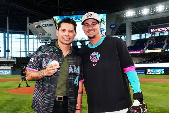 Dos hombres en campo de béisbol sonriendo.