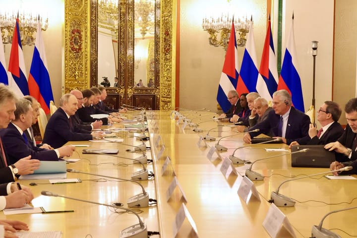 Reunión diplomática internacional en salón dorado, banderas presentes.