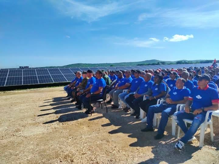 Personas en reunión junto a paneles solares.