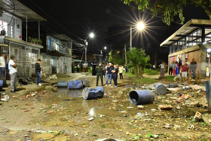 Calle inundada con escombros y personas observando.