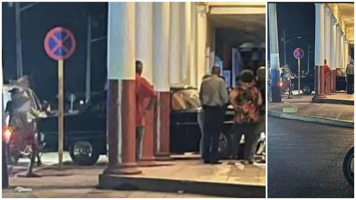 Gente junto a señal de no estacionar en la noche.