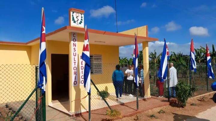 Consultorio médico con banderas, personas afuera.
