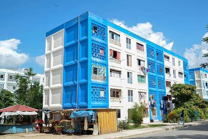 Edificio residencial colorido con balcones y árboles.