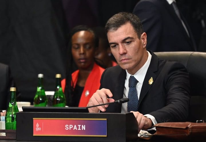 Hombre serio en reunión G20 con cartel de España