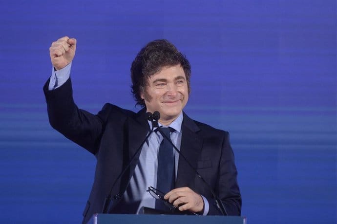 Hombre sonriendo en podio con gesto de victoria