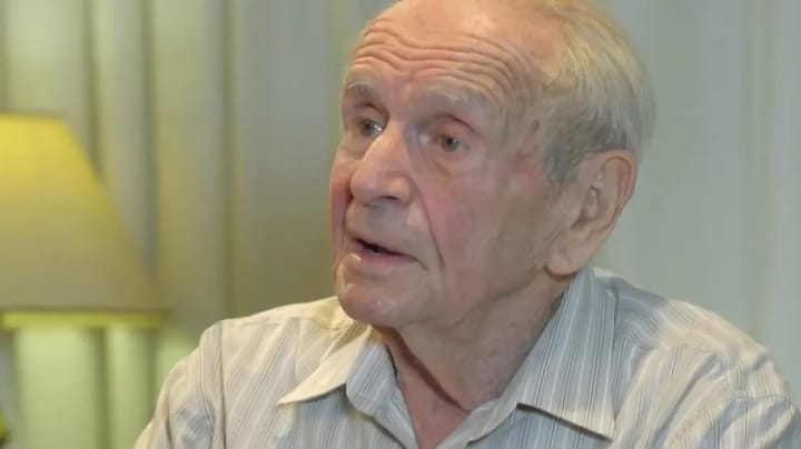 Hombre mayor con camisa, mirando a la derecha.