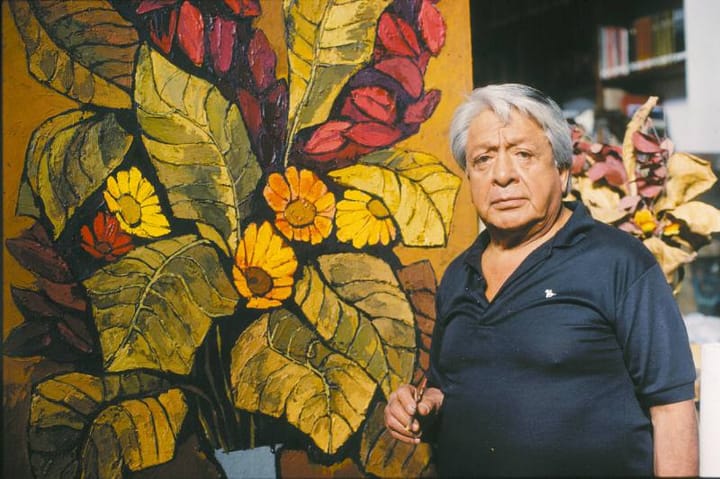 Hombre mayor junto a pintura grande de flores coloridas