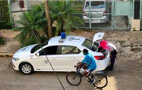 Persona revisa maletero de taxi, ciclista pasa