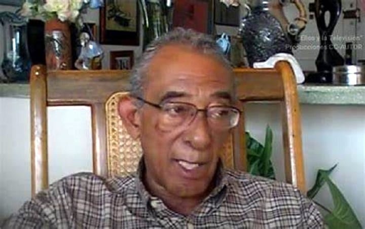 Hombre mayor hablando en interior, camisa de cuadros