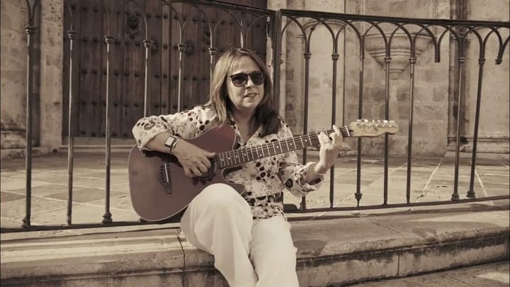 Mujer tocando guitarra en exterior histórico