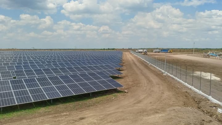 Gran campo de paneles solares bajo cielo azul.