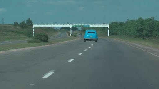 Coche azul en carretera despejada con puente